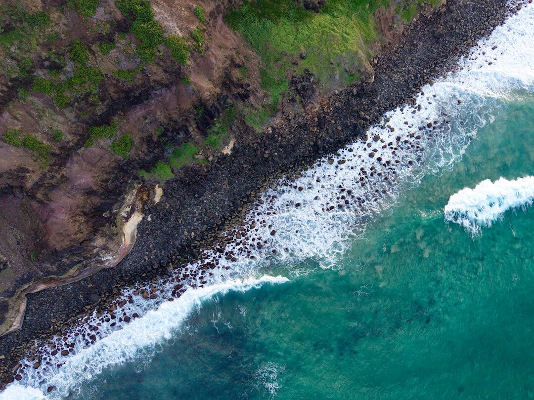 Aerial drone view of José Ignacio coastline at golden hour with waves breaking on rocky shore